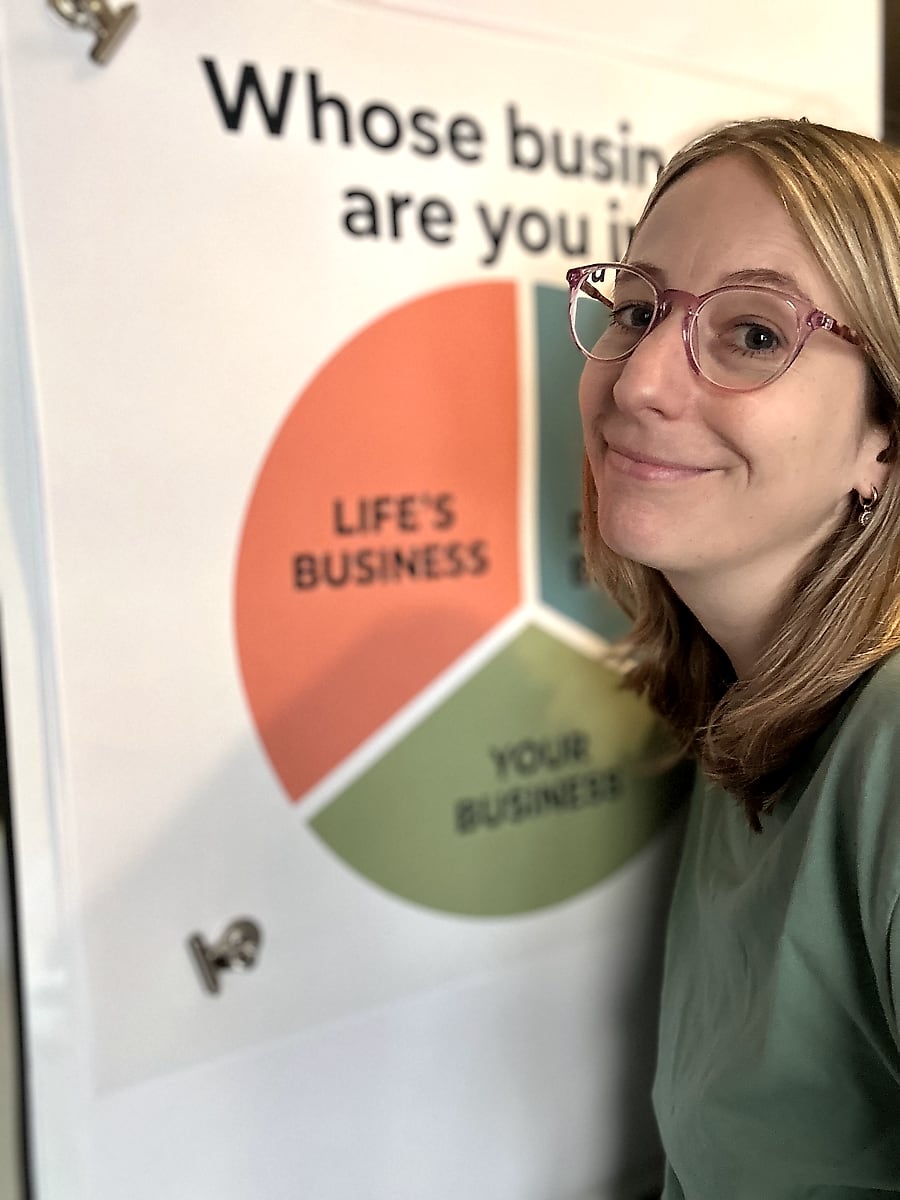 Tamara smiling next to her poster: Whose business are you in? Your business, other people's business, life's business