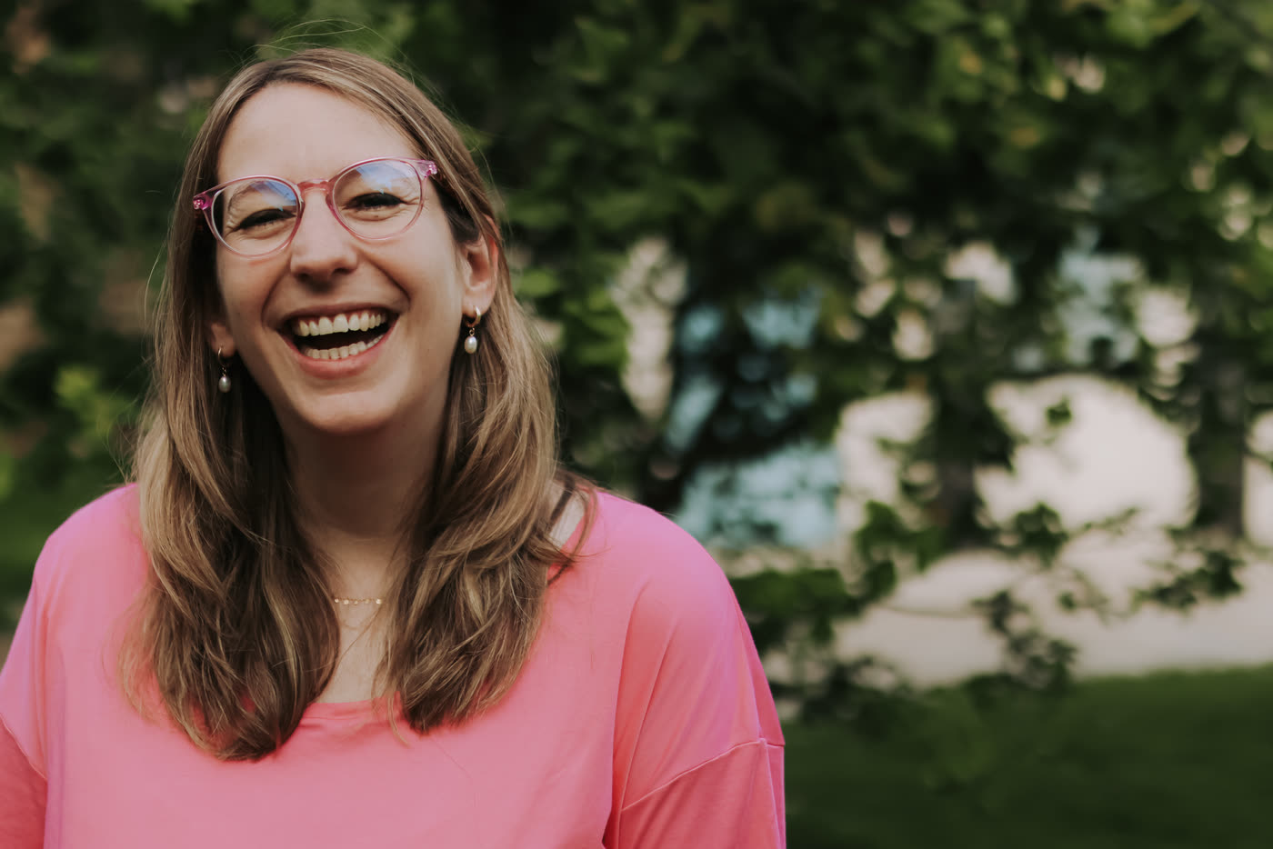 Tamara laughing in a pink t-shirt, trees behind her
